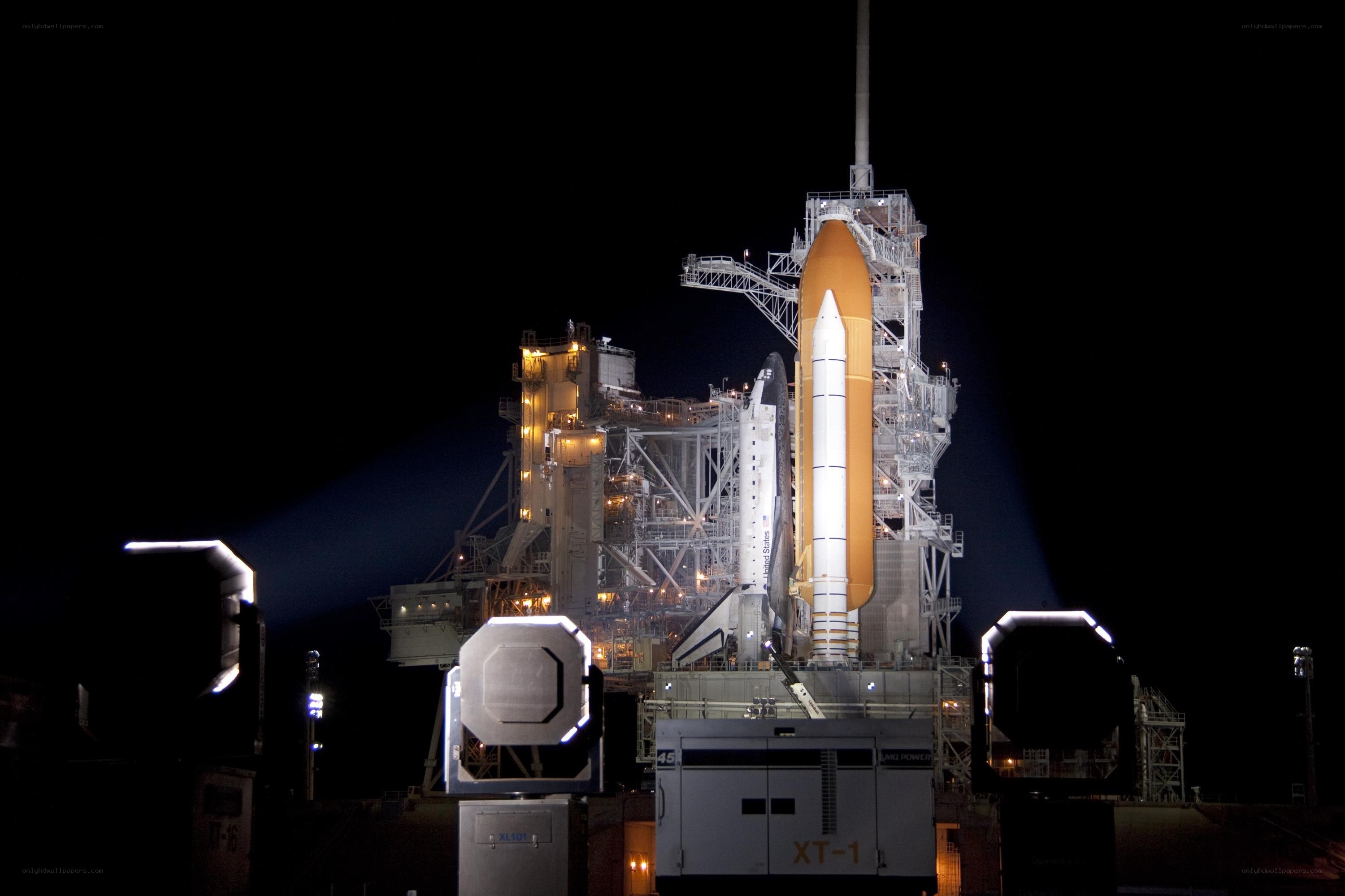 Space shuttle on launch pad at night