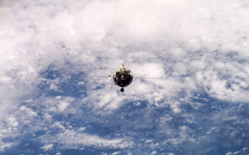 spacecraft above Earth clouds