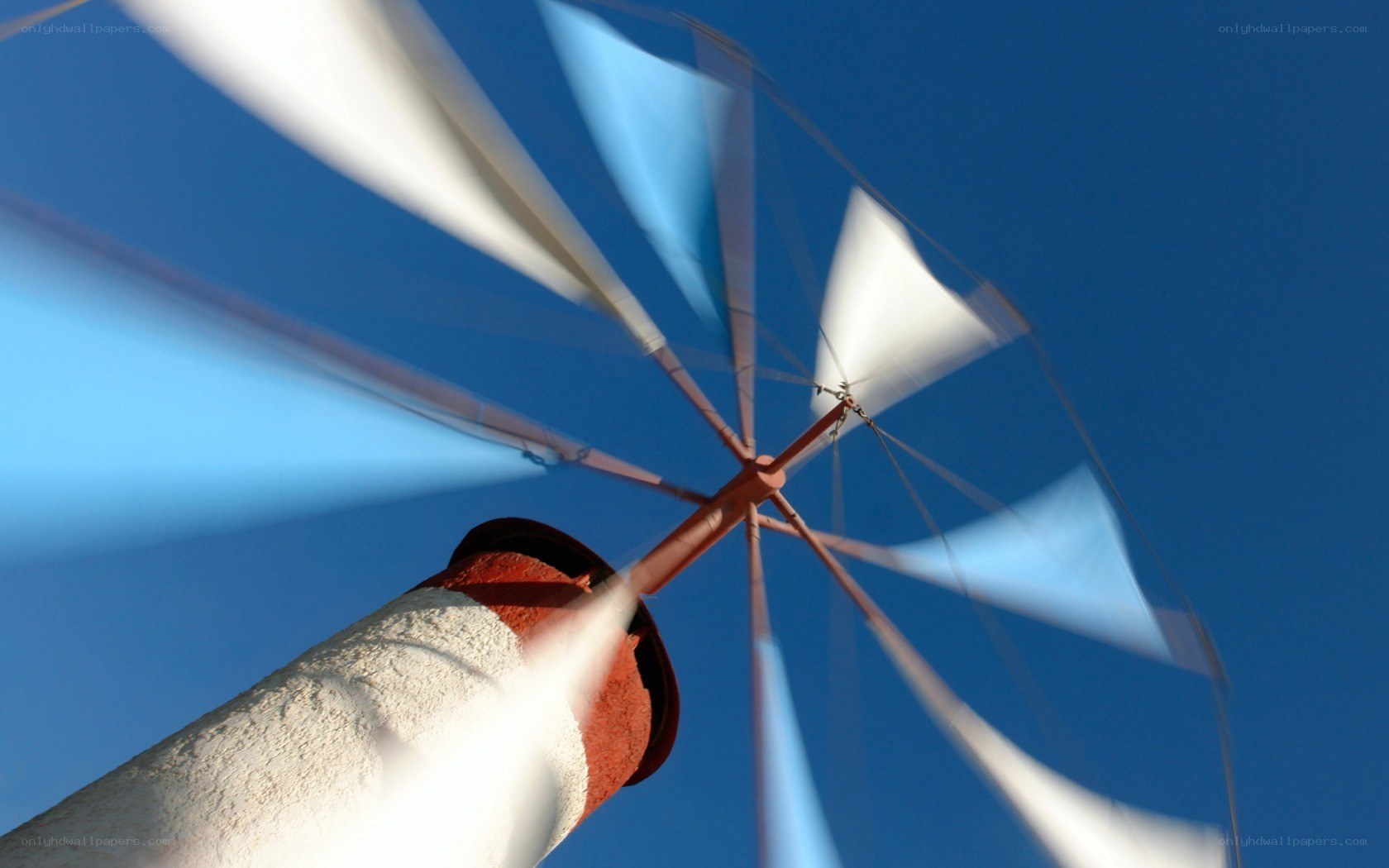 Spinning windmill against blue sky