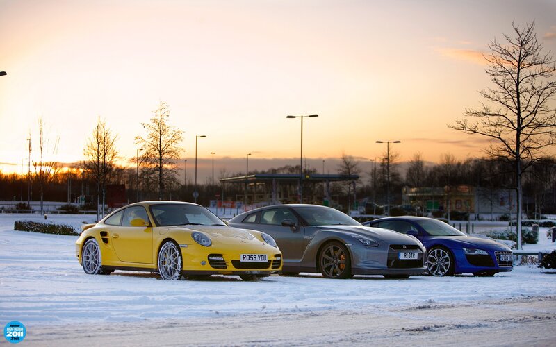 Sports cars in snow at sunset