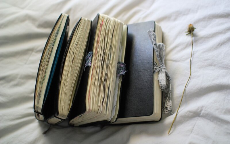 stack of journals on bed