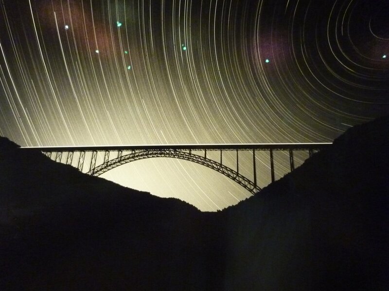 Star trails over a bridge