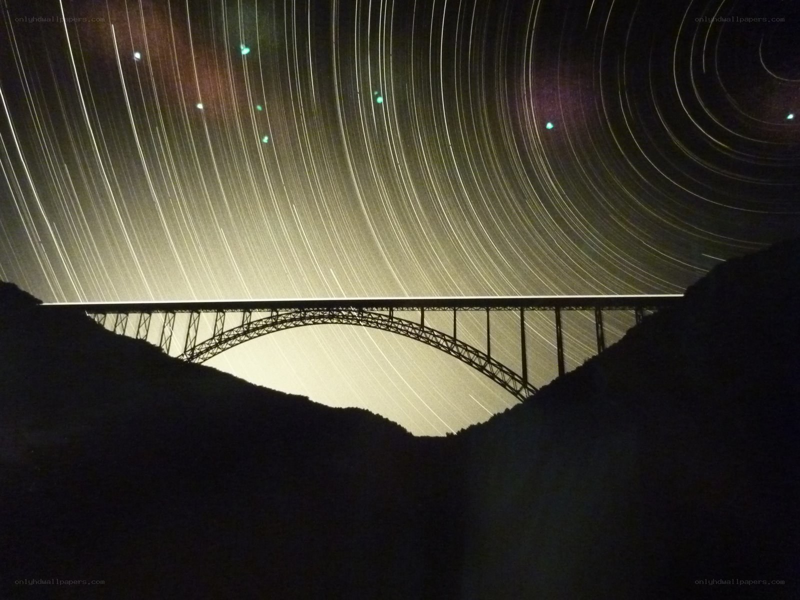 Star trails over a bridge