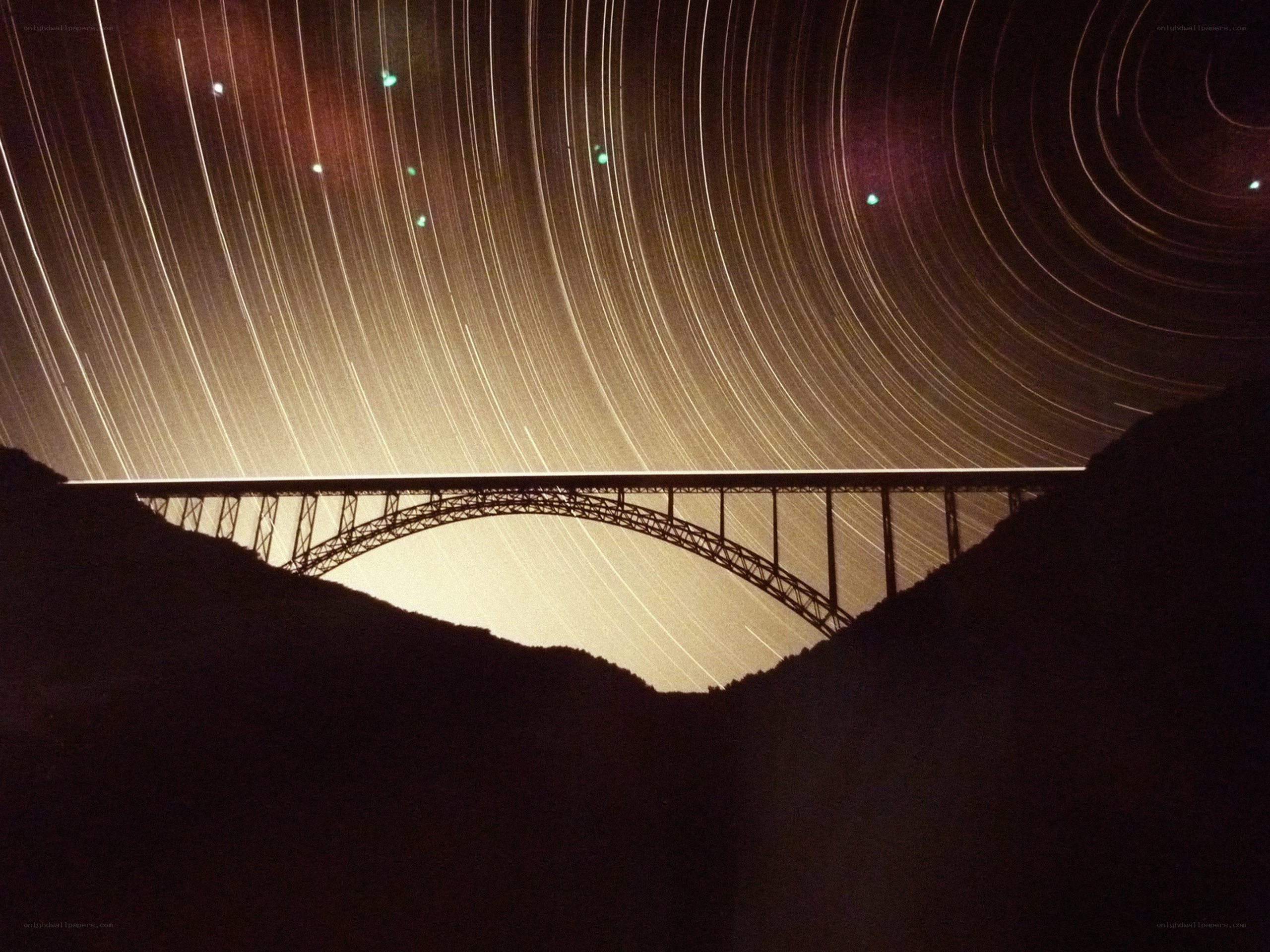 Star trails over a bridge