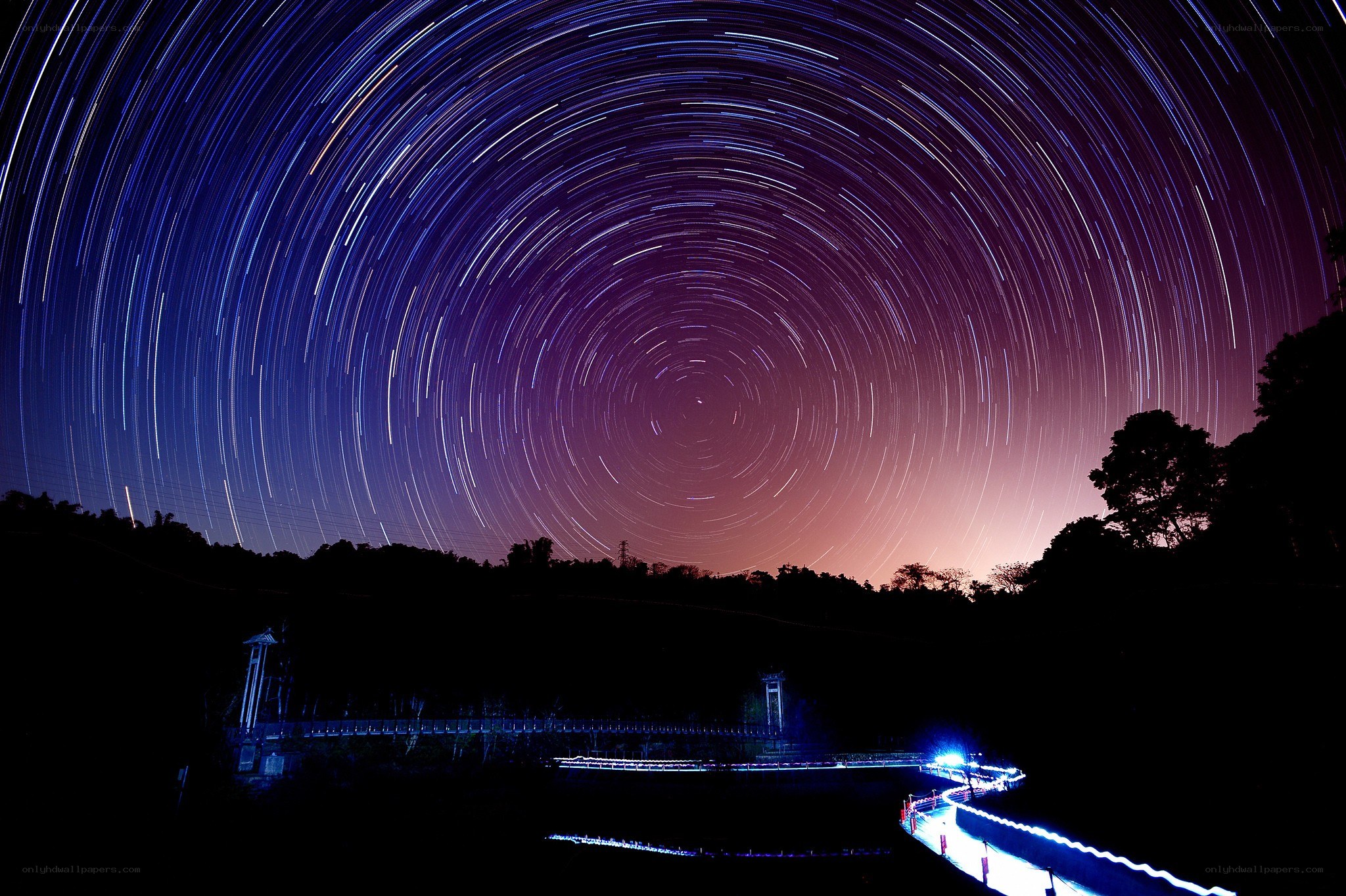 Star trails over a bridge at night