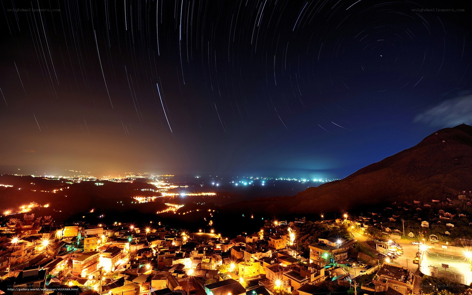 Star trails over a coastal town