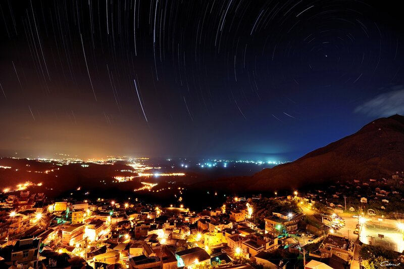 Star trails over a coastal village