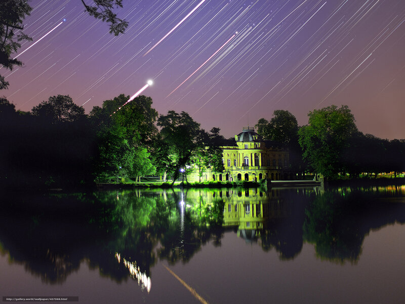 Star trails over a lake and mansion