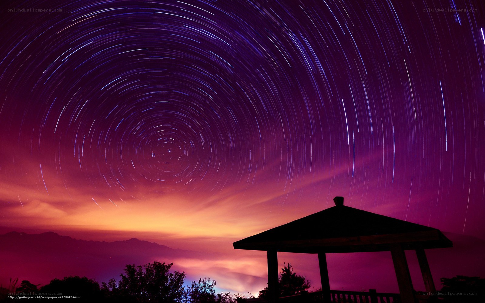 Star trails over a mountain pavilion