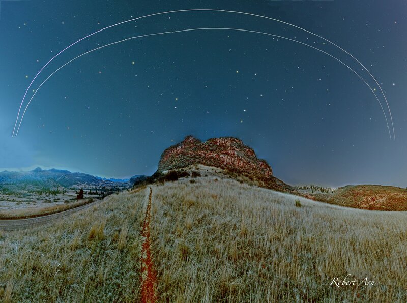 Star trails over a rocky hill