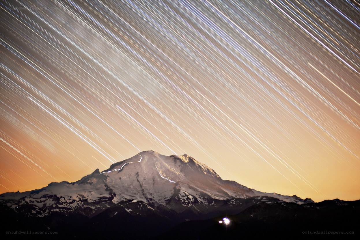Star trails over a snow-capped mountain