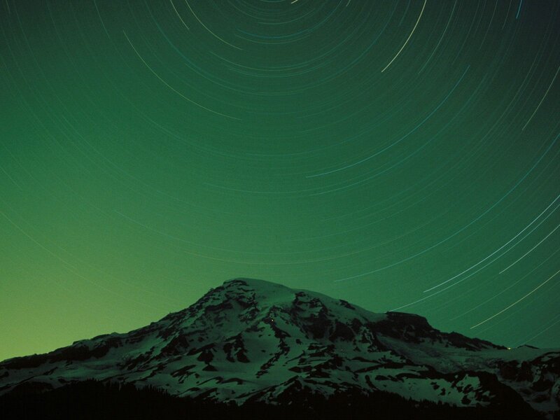 Star trails over a snow-capped mountain