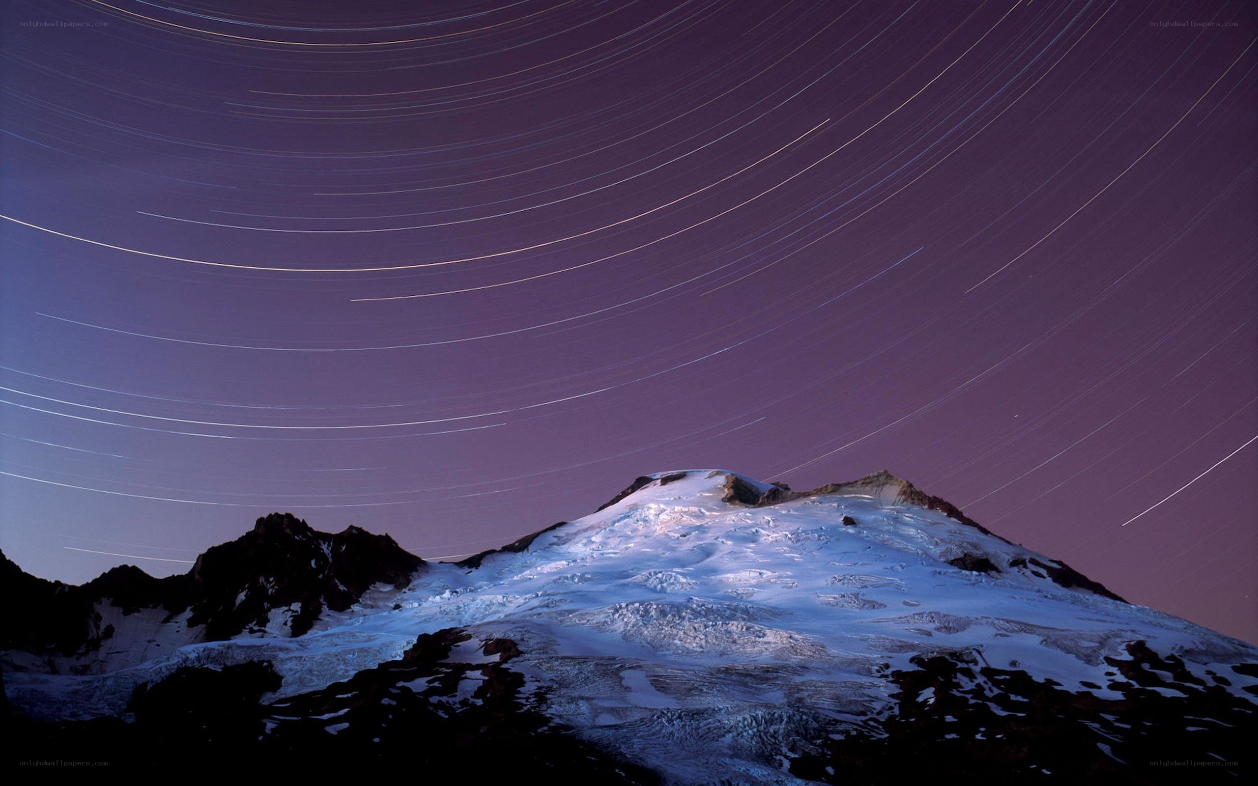 Star trails over a snow-capped mountain