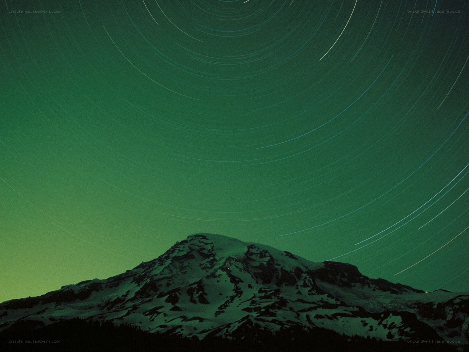 Star trails over a snow-capped mountain