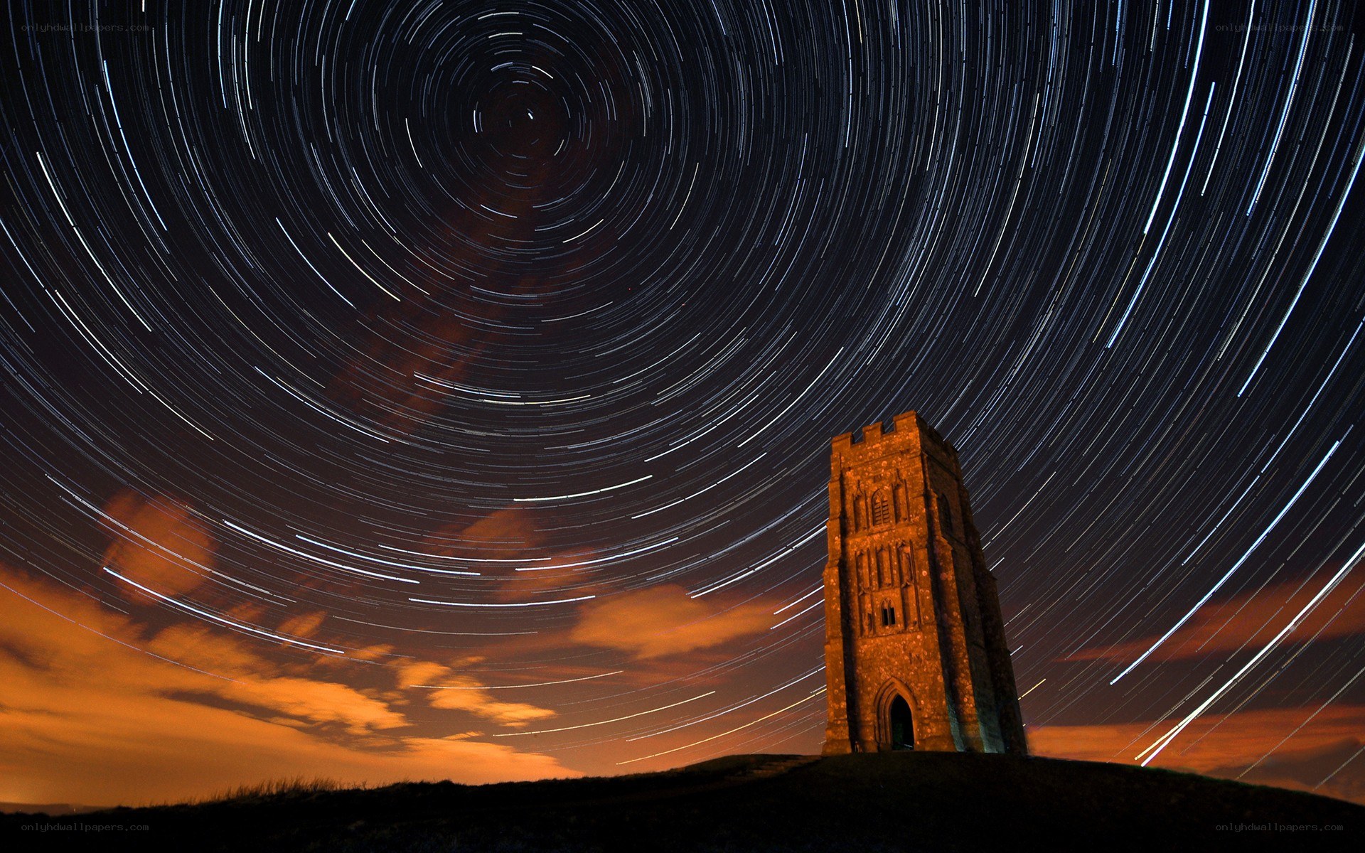Star trails over a stone tower