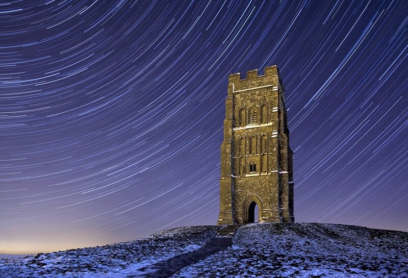 Star trails over a stone tower