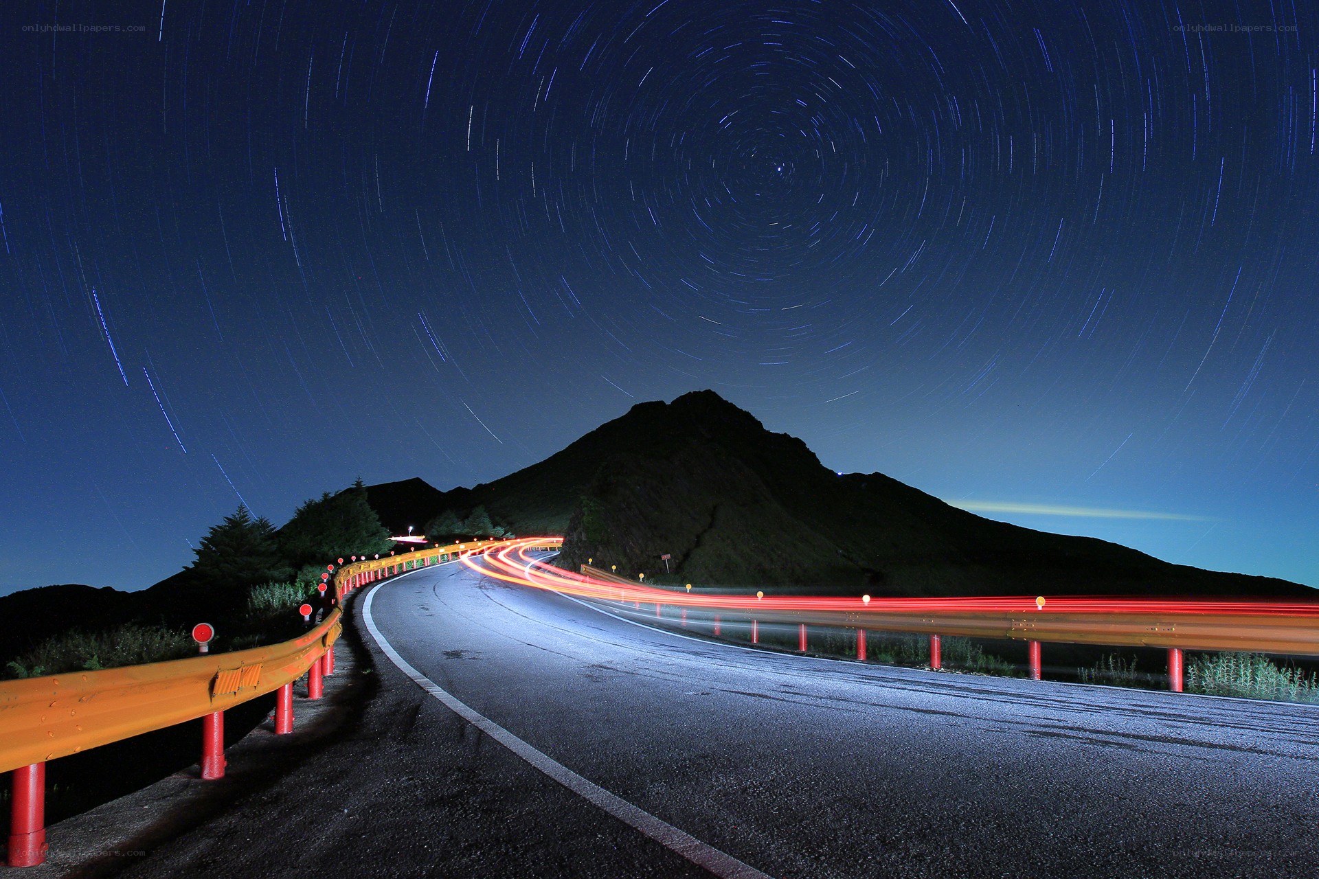 Star trails over a winding road