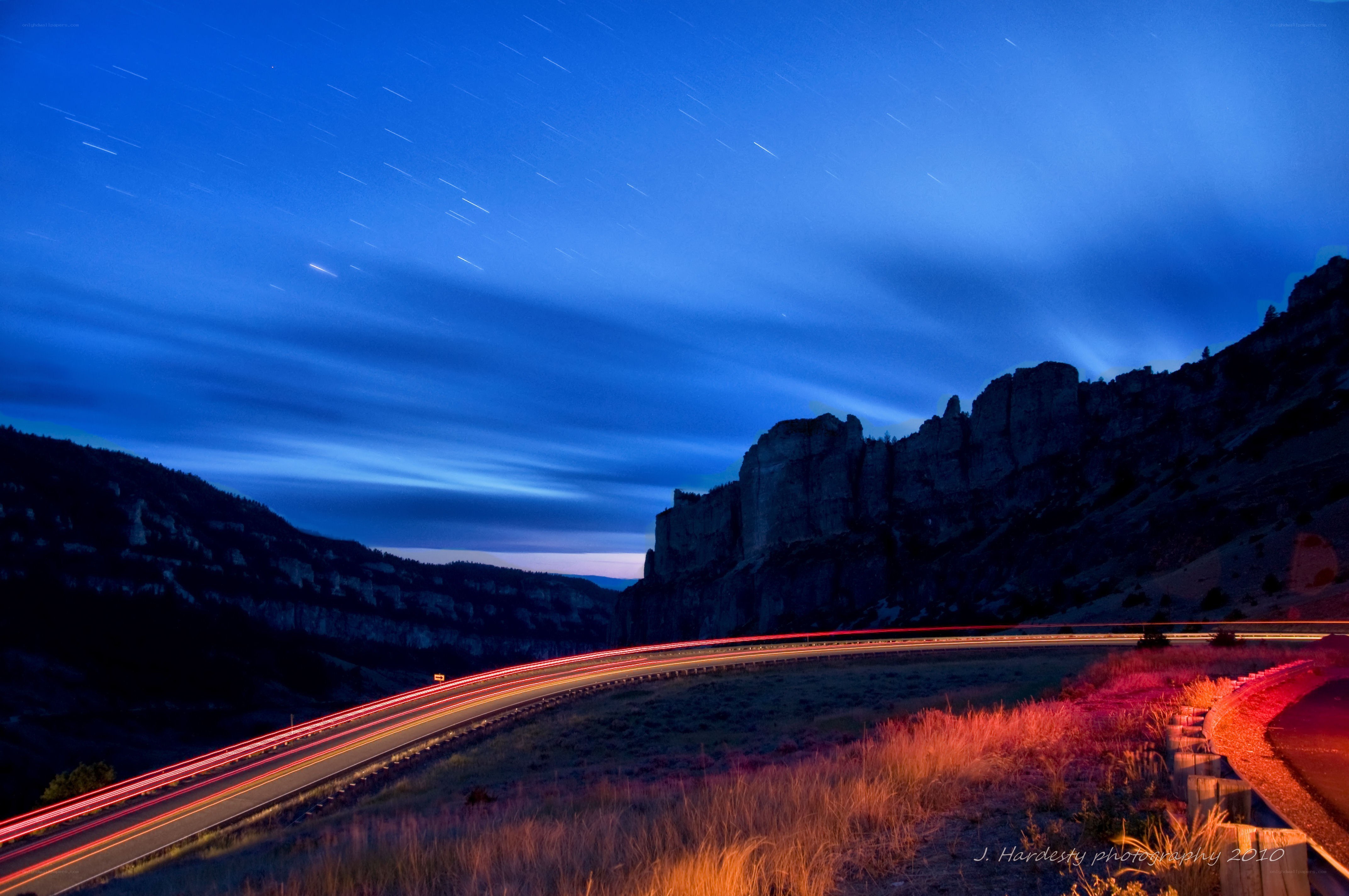 Star trails over a winding road
