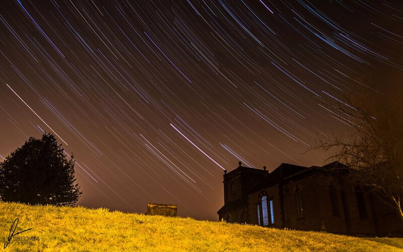 Star trails over church at night
