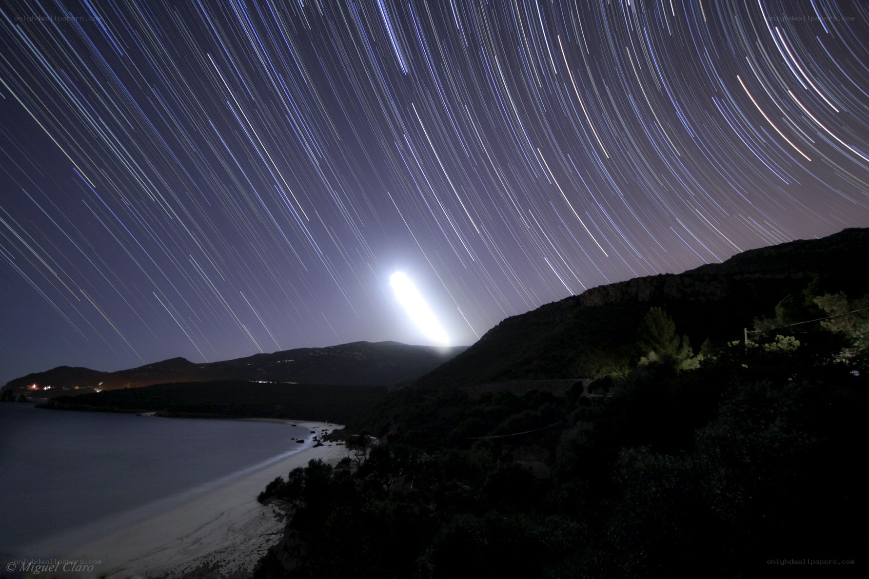 Star trails over coastal landscape