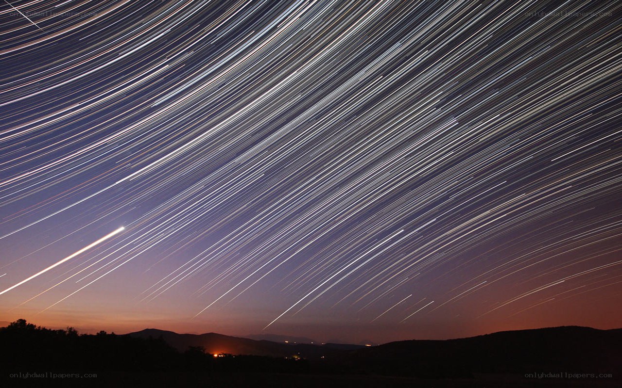 Star trails over hills at night