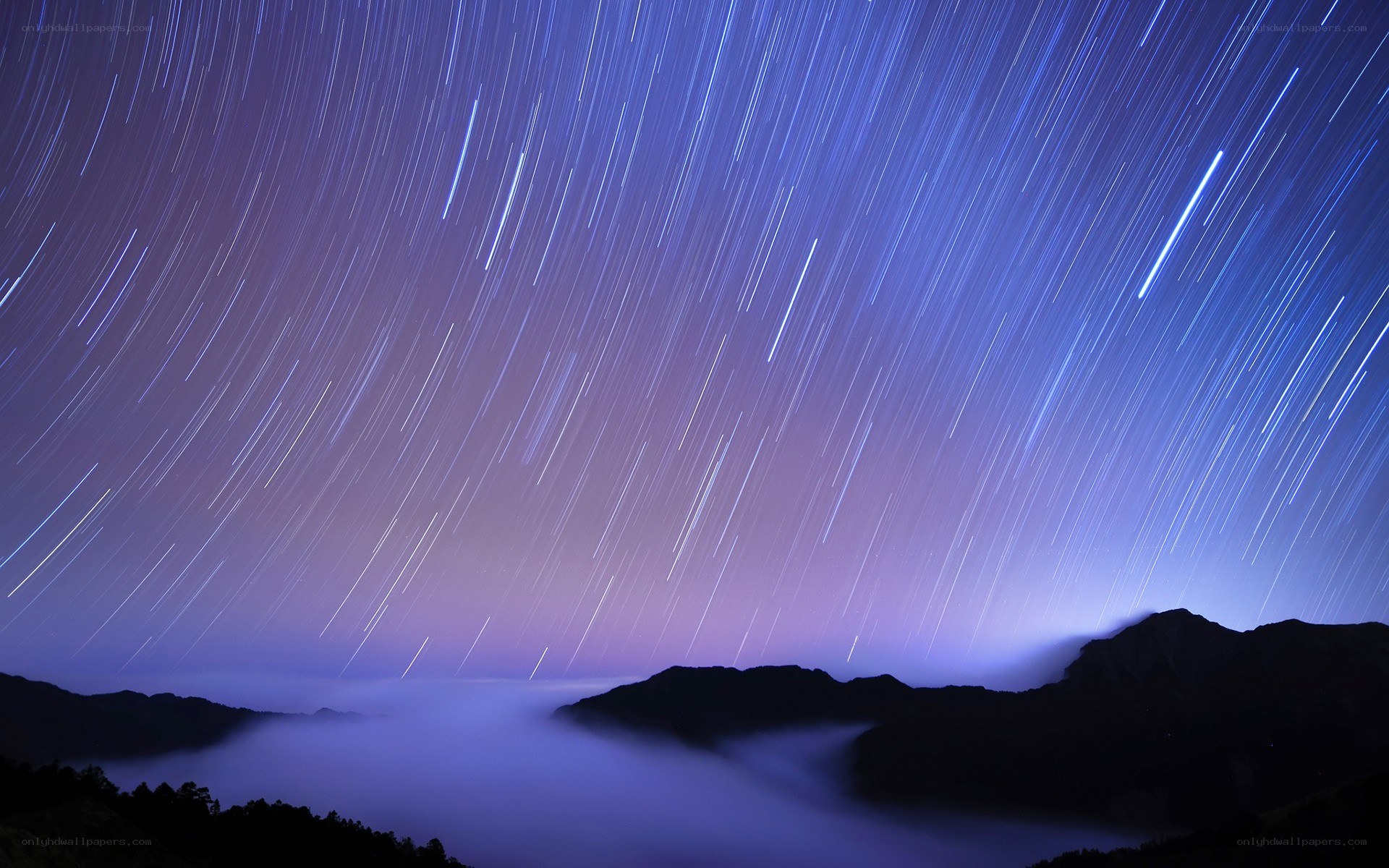 Star trails over mountain fog