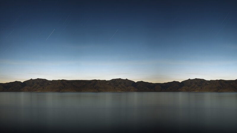 Star trails over mountain lake