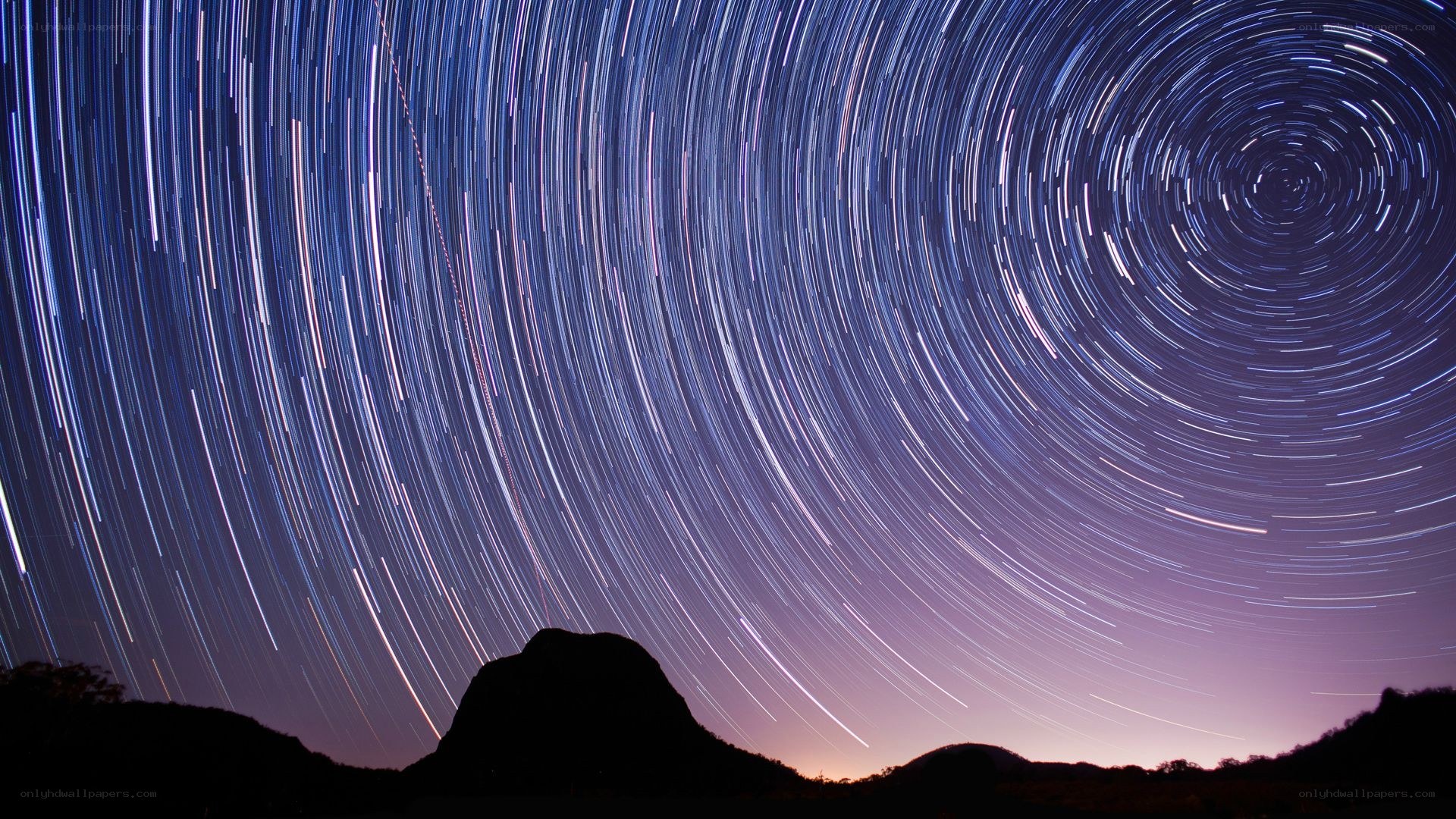 Star trails over mountain silhouette
