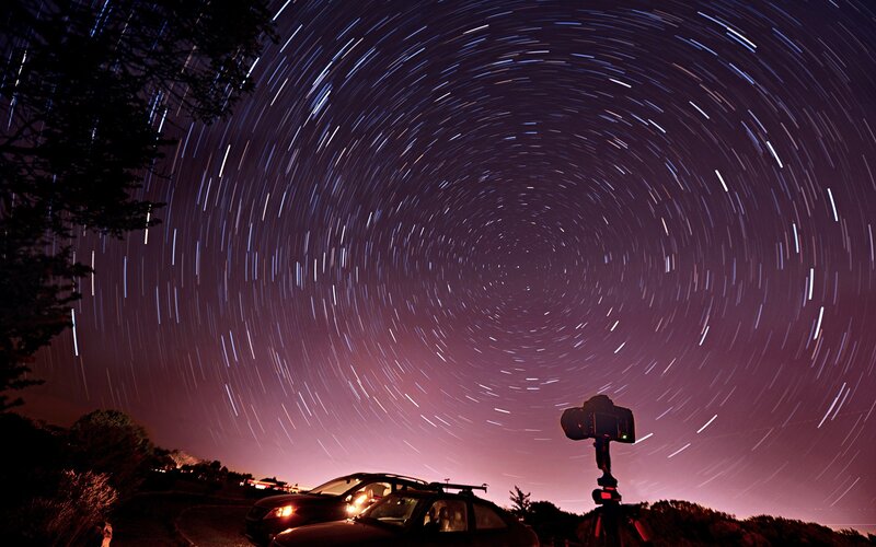 Star trails over parked cars