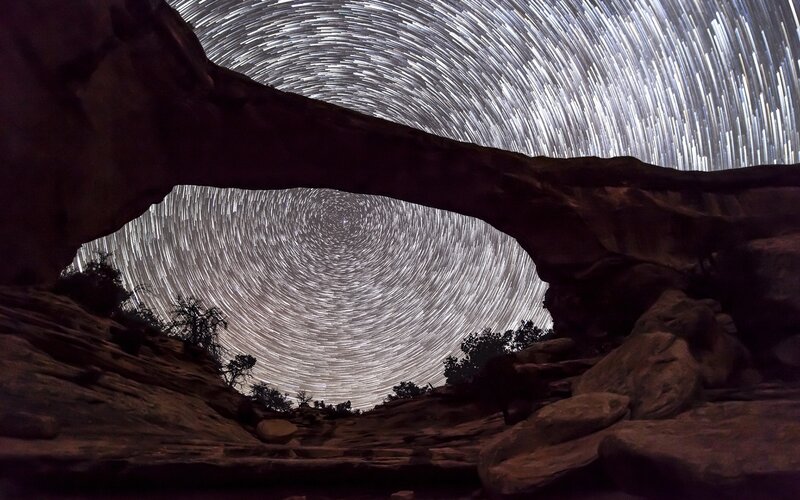 Star trails over rock arch