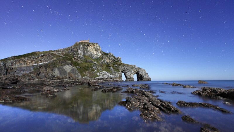 Star trails over rocky island