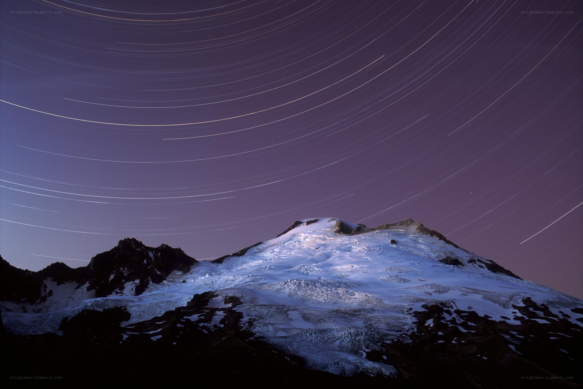 Star trails over snow-capped mountain