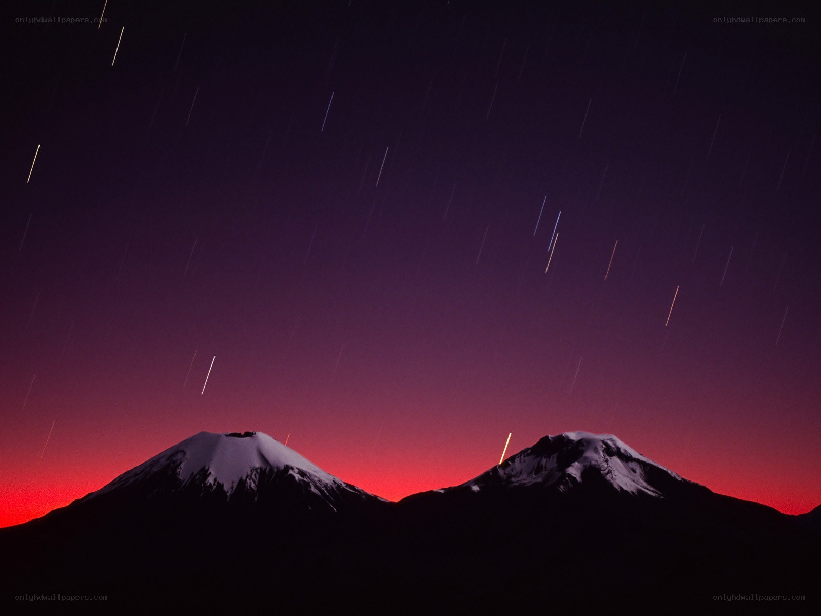 Star trails over snow-capped mountains