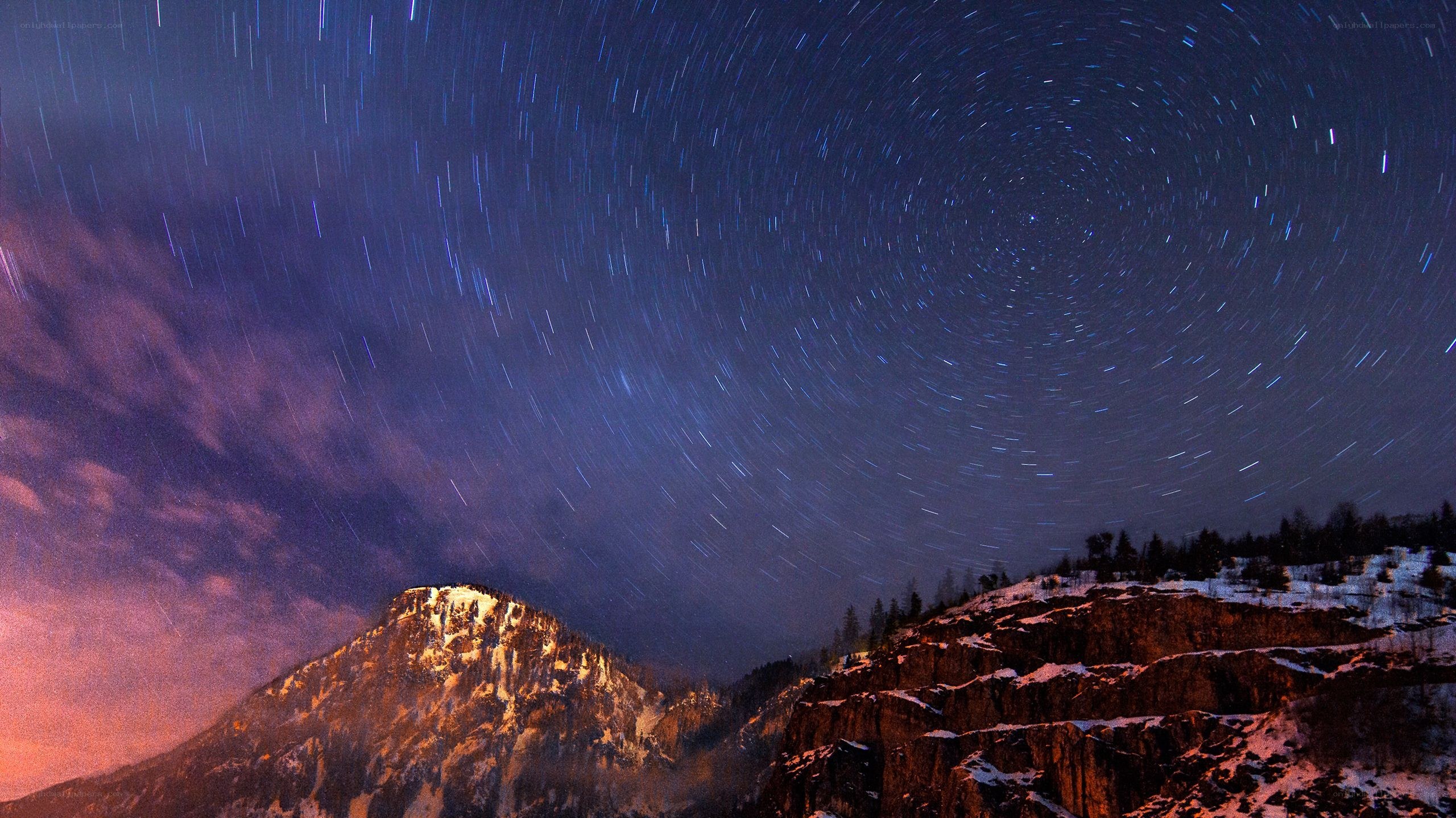 Star trails over snowy mountains