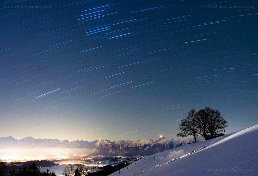 Star trails over snowy mountains