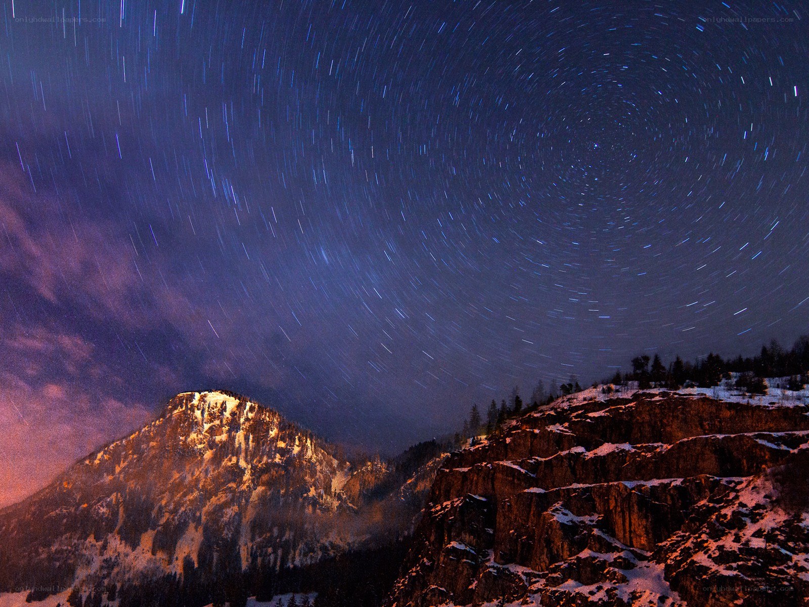 Star trails over snowy mountains