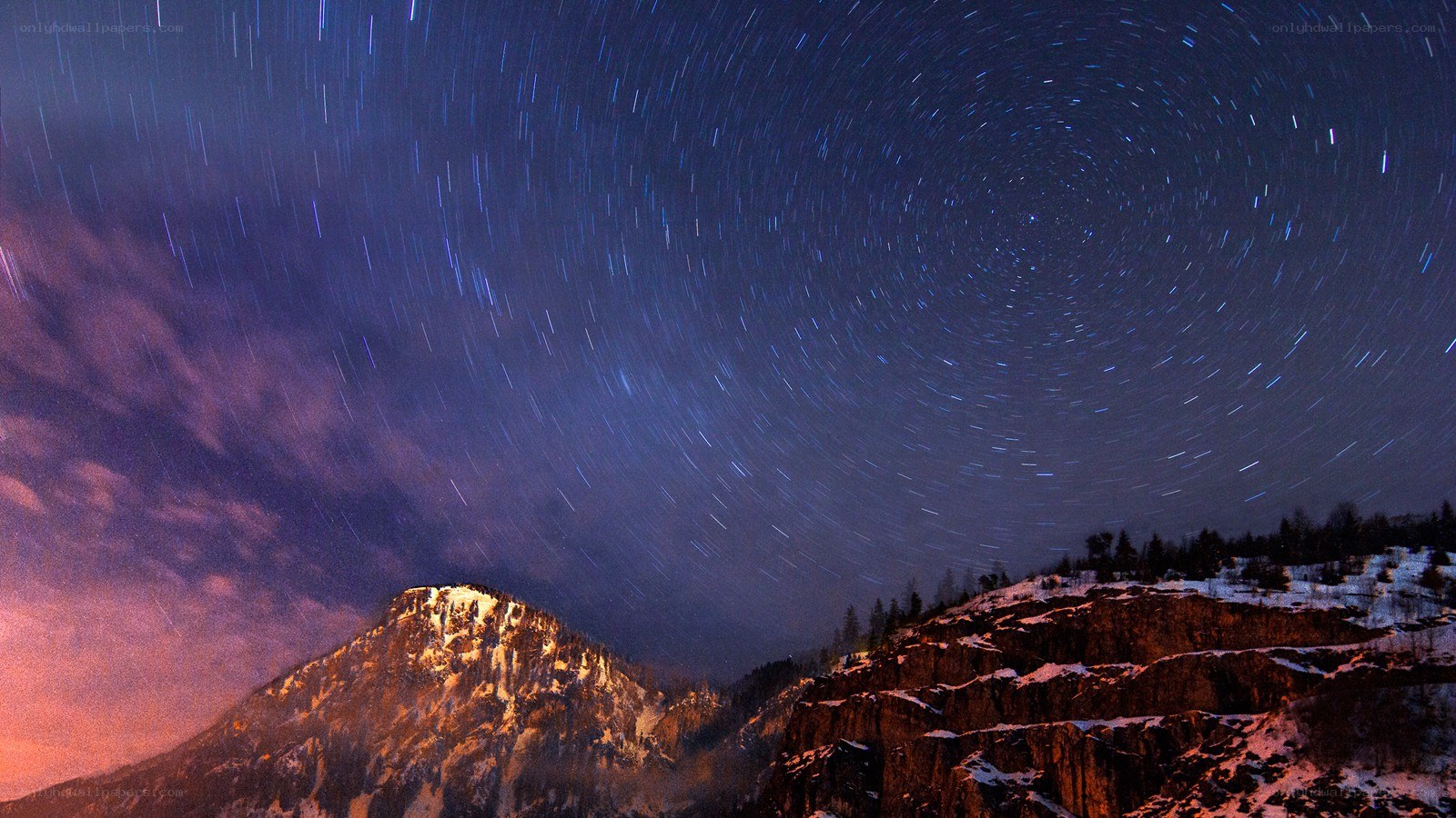 Star trails over snowy mountains
