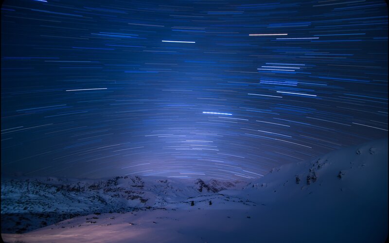Star trails over snowy mountains
