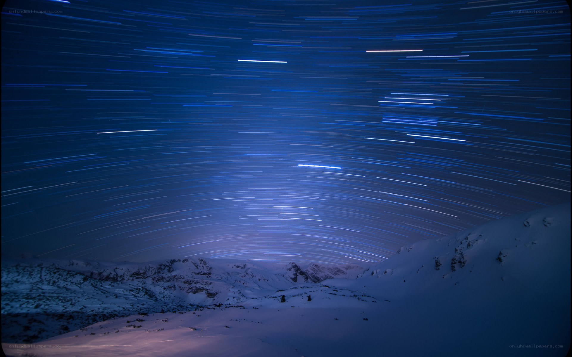 Star trails over snowy mountains
