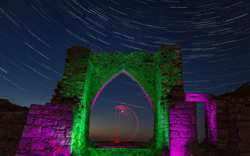 Star trails over stone arch