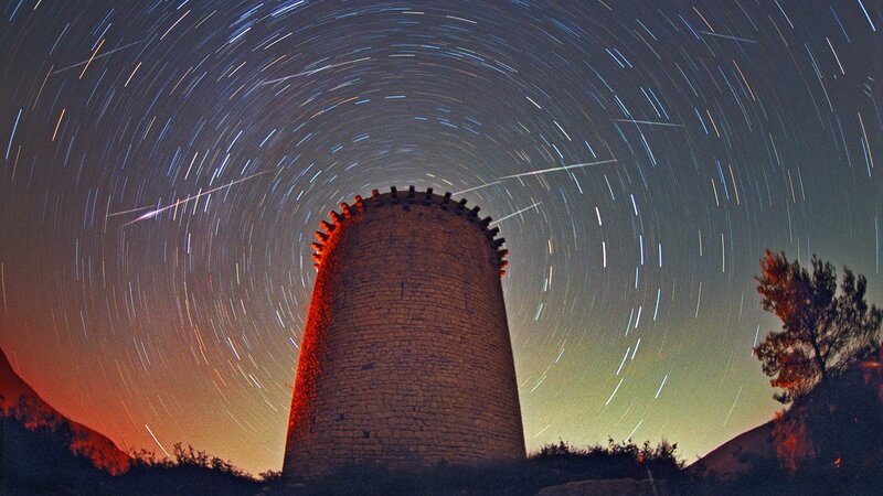 Star trails over stone tower