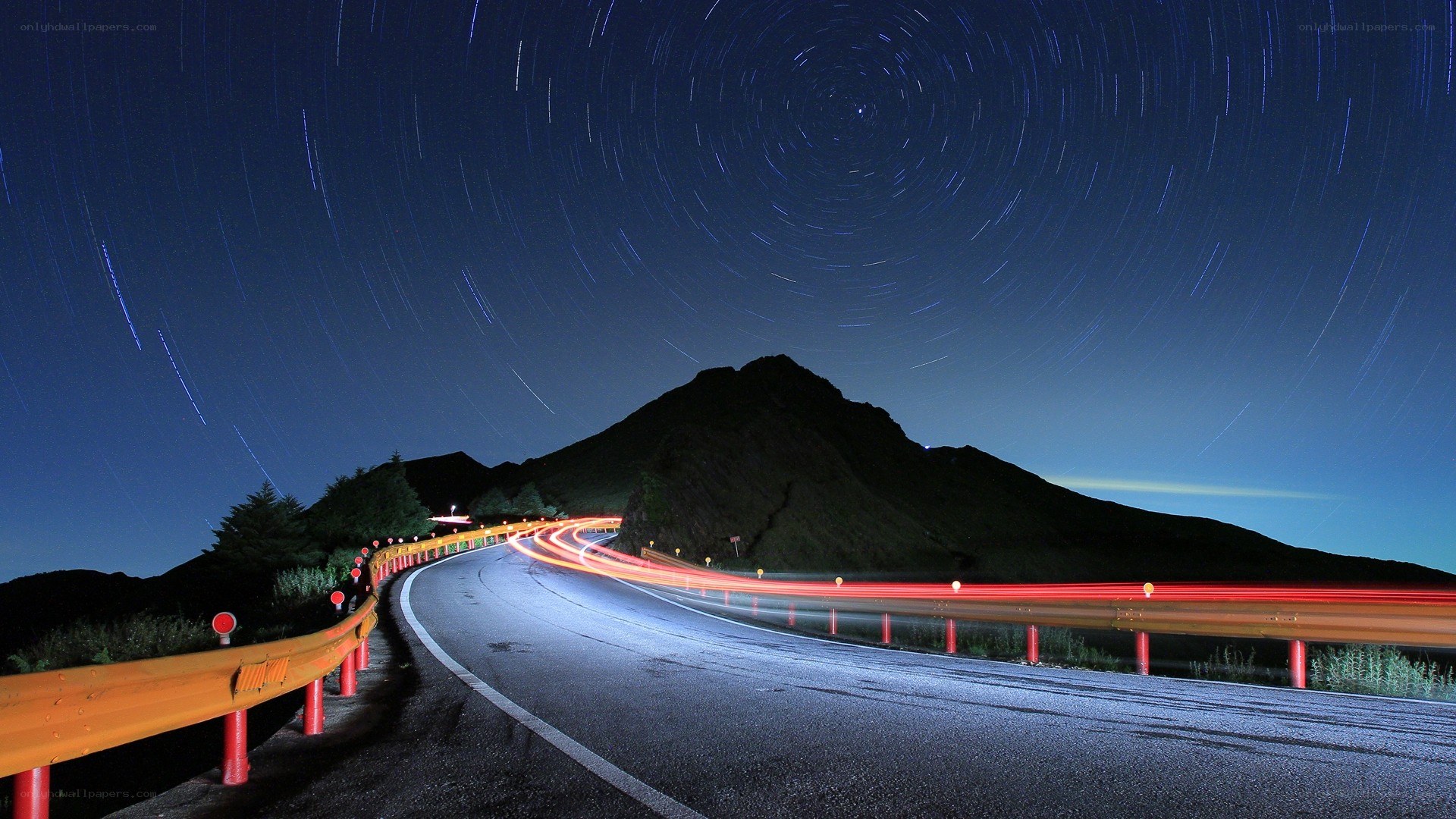 Star trails over winding mountain road