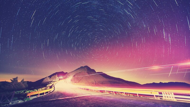 Star trails over winding mountain road