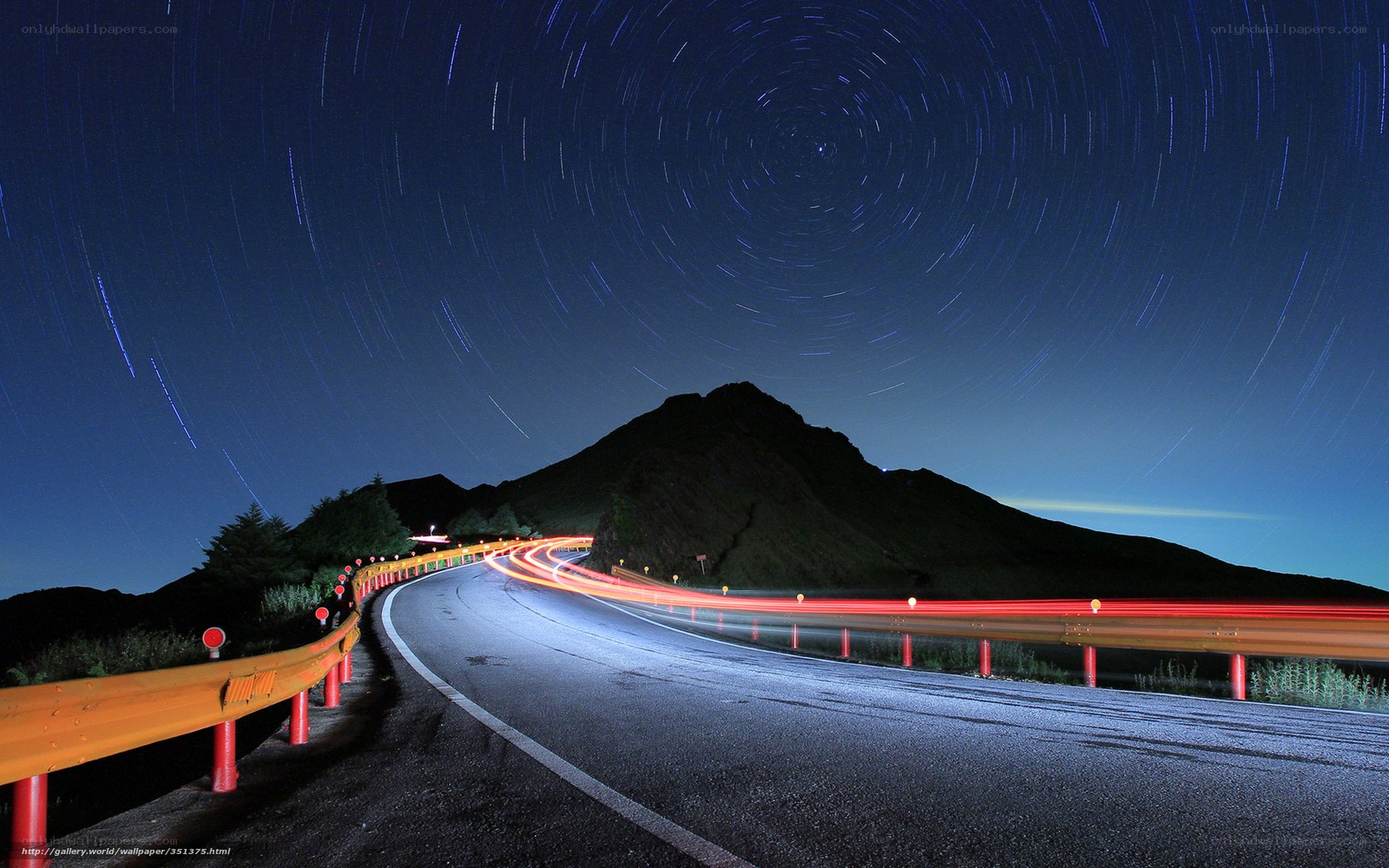 Star trails over winding mountain road