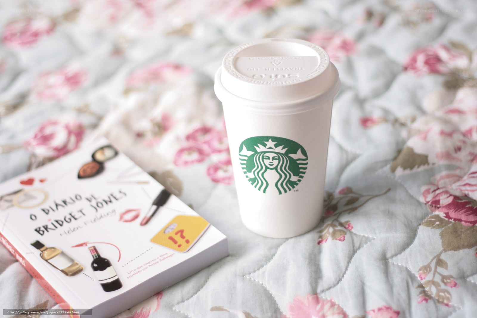 Starbucks cup and book on bed