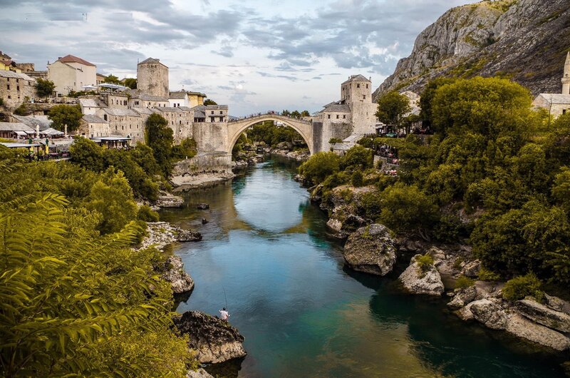 Stari Most Bridge — Blue, Serene, Afternoon, Photograph, River, Town, Mountain, Trees