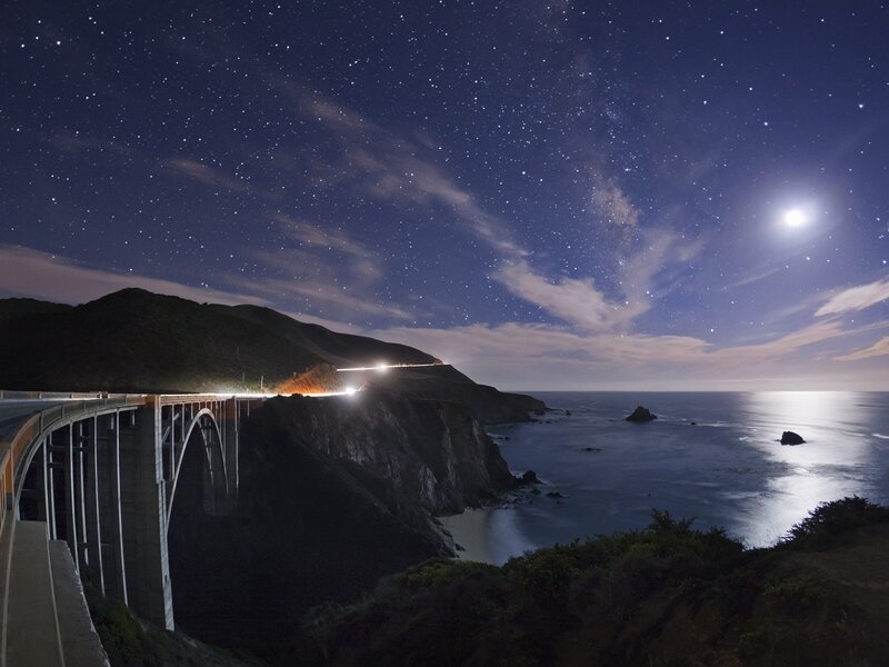 Starlit bridge over ocean at night