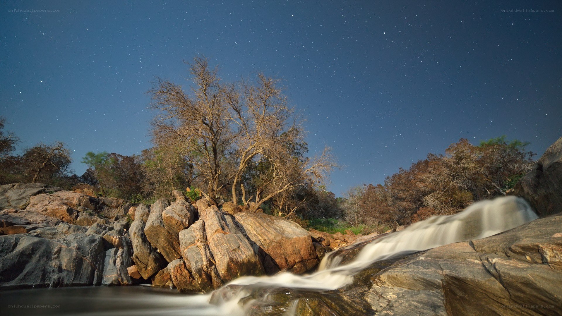 Starlit waterfall at night