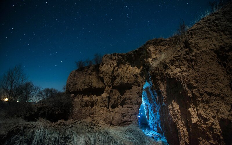 Starry night at a cliffside cave
