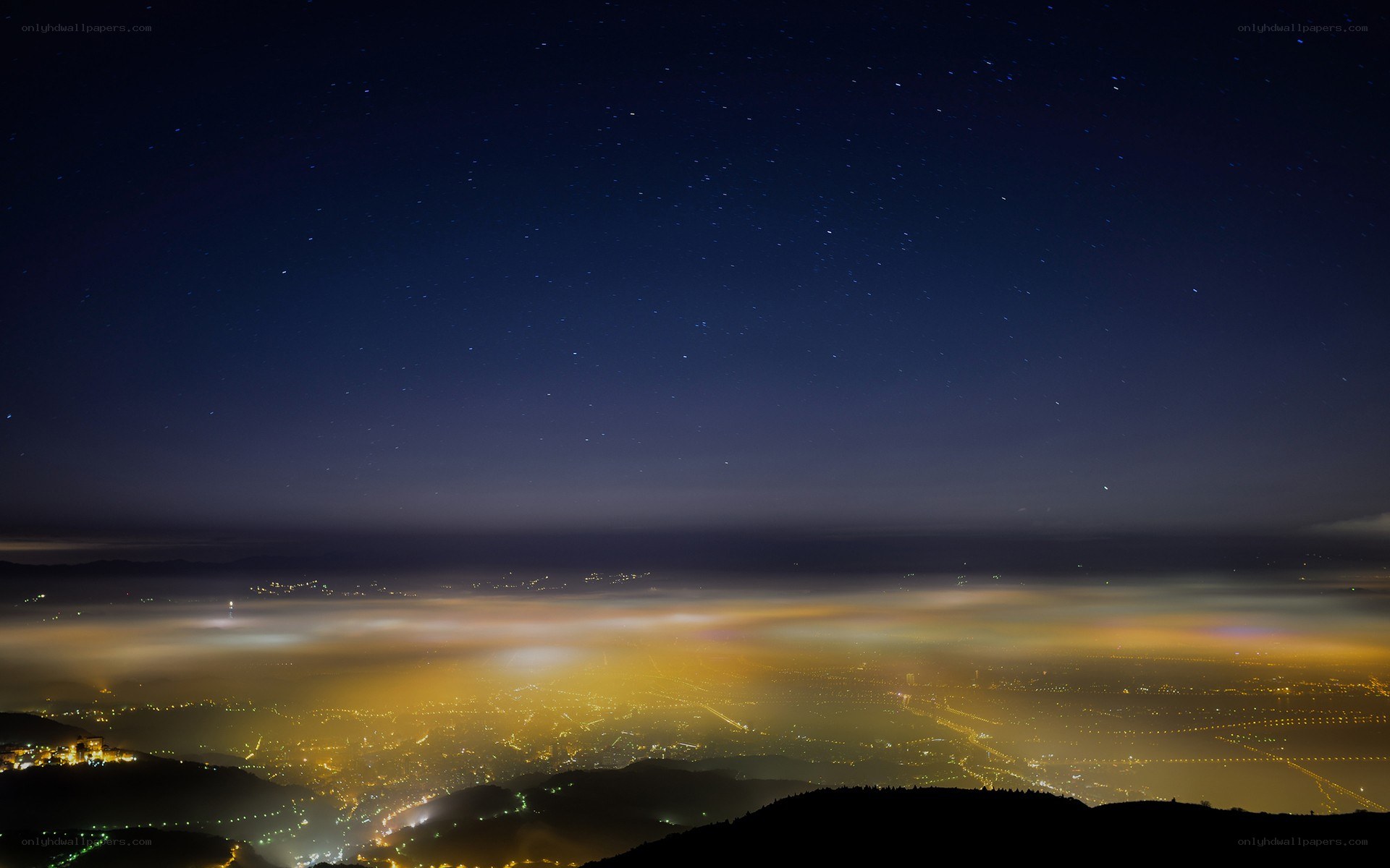 Starry night over city and clouds